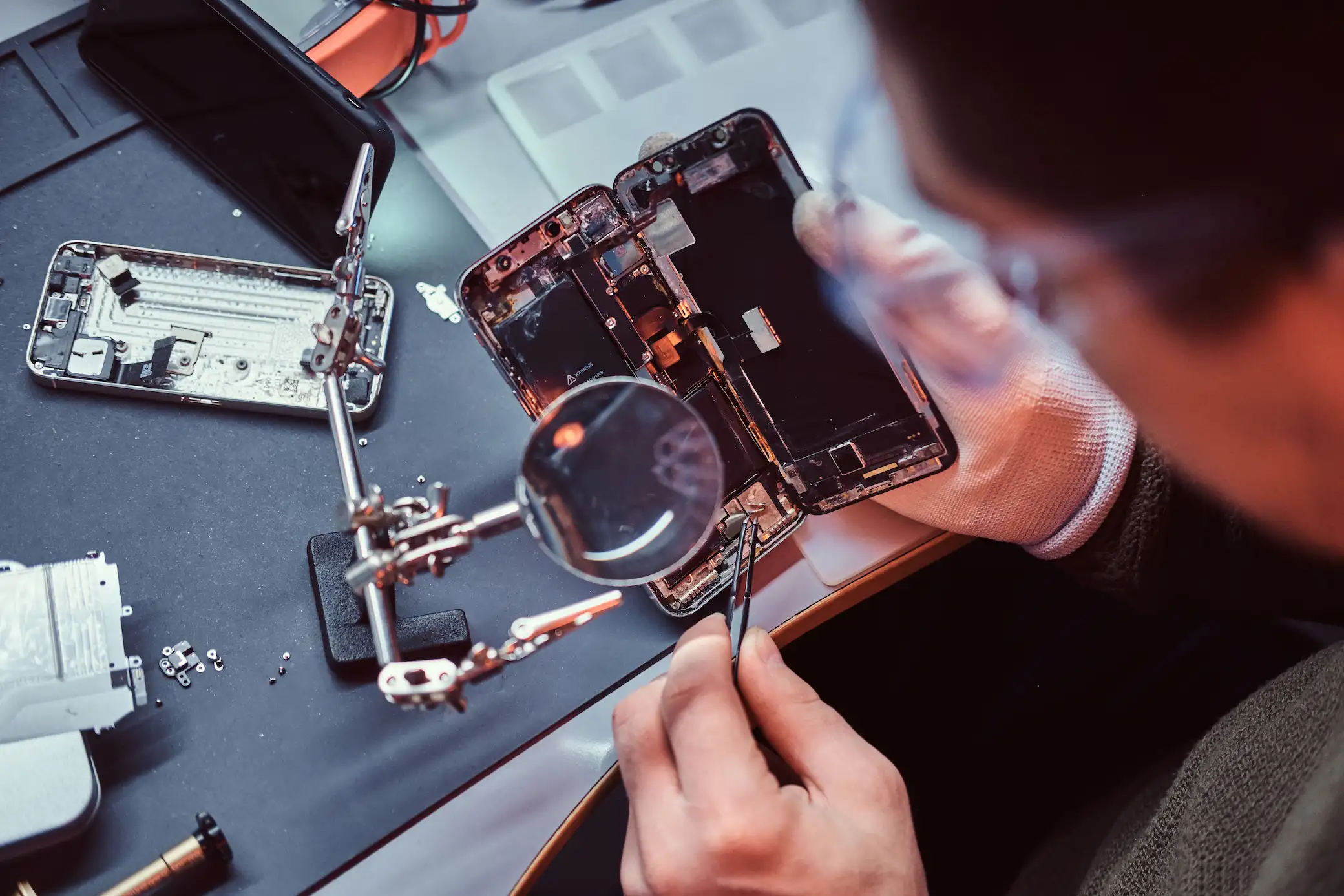 repairman uses magnifier tweezers repair damaged smartphone close up photo disassembled smartphone